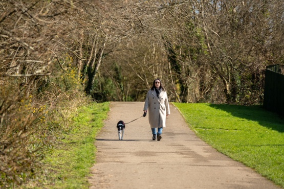A lady walking a dog in the park