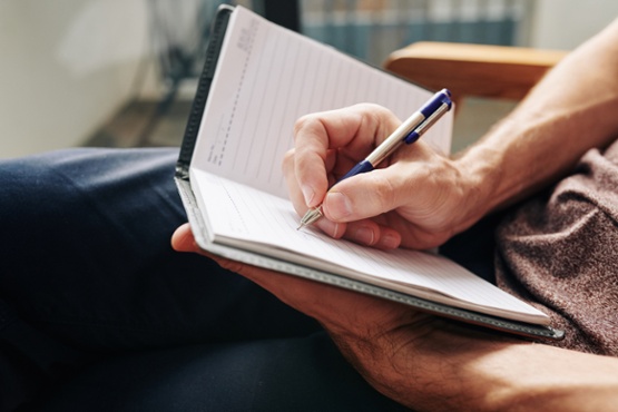 person making notes in notepad